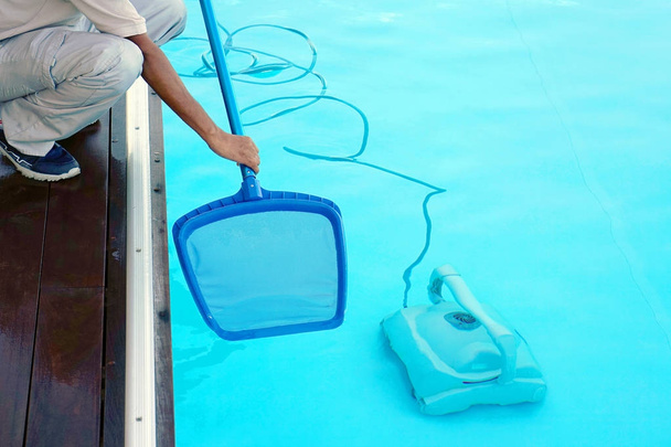 Funcionário do hotel limpando a piscina
 - Foto, Imagem