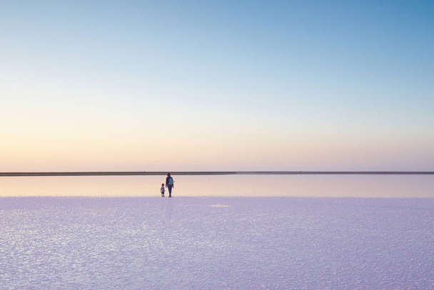 Mother and child walking on a salt and brine of a pink lake, colored by microalgae Dunaliella salina - Fotografie, Obrázek
