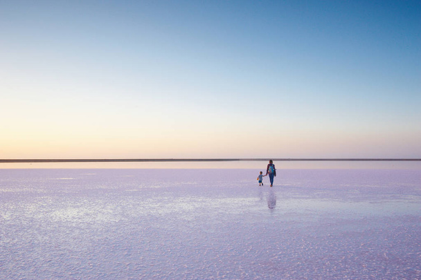 Mother and child walking on a salt and brine of a pink lake, colored by microalgae Dunaliella salina - Fotografie, Obrázek