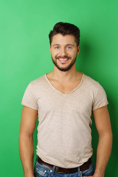 Smiling young man posing against green background - Foto, Imagem