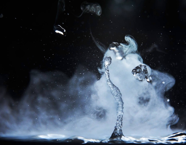 Boiling water splash with steam on black background closeup - Foto, Bild