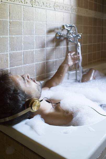 голий хлопець у ванній кімнаті з смартфоном та навушниками
 - Фото, зображення