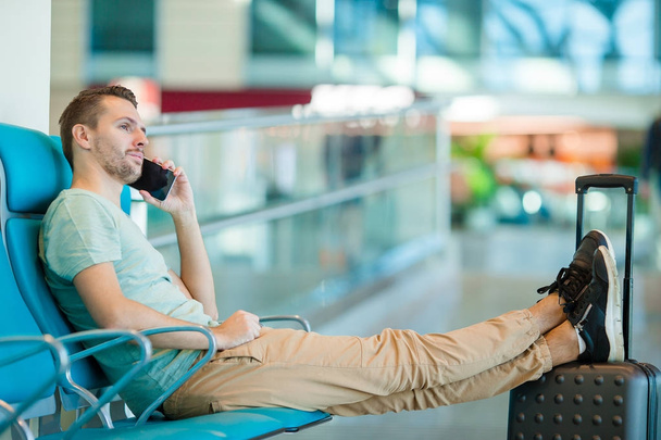 Mladý muž v letištní hale čeká na letu letadla. Kavkazská muž s smartphone vnitřní - Fotografie, Obrázek