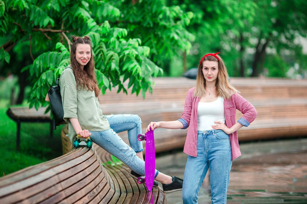Due ragazze hipster con skateboard all'aperto nel parco. Donne sportive attive che si divertono insieme nello skate park
. - Foto, immagini