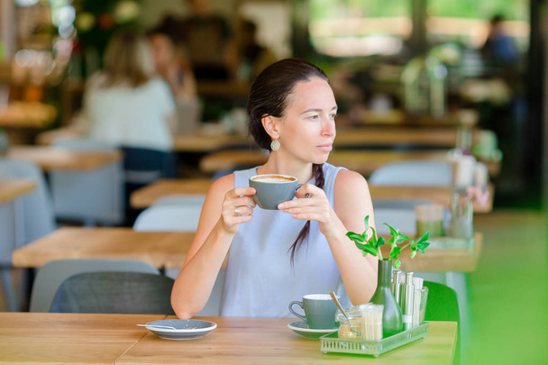 Элегантная девушка, завтракающая в открытом кафе. Счастливая городская женщина пьет кофе
 - Фото, изображение