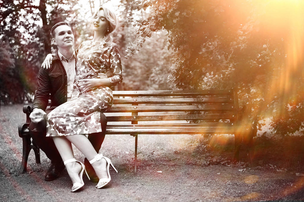 beautiful young woman and handsome man sitting on bench in park. Love couple at date outdoor, black and white  - Fotó, kép