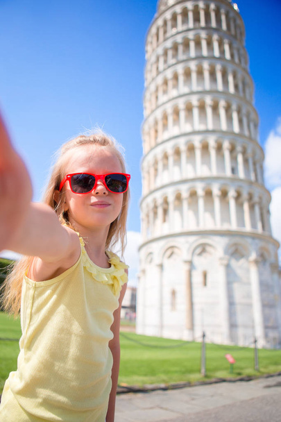 Маленька дівчинка, яка бере selfie фон Пізанська вежа в Пізе, Італія - Фото, зображення