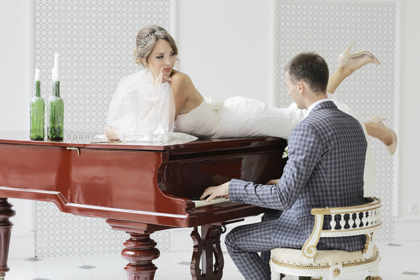 groom playing grand piano and bride - Foto, afbeelding
