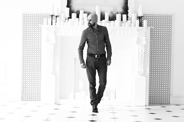 portrait of handsome bald bearded man posing near white fireplace with candles  - Fotografie, Obrázek