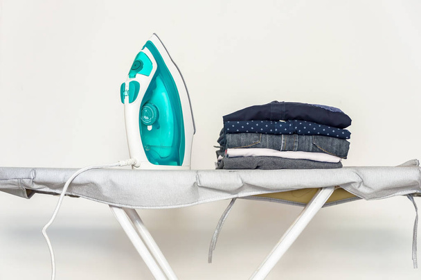 Ironing clothes on ironing board,Pile of clothes in the white ro - Фото, изображение