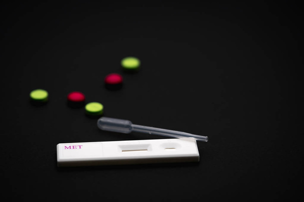 Τεστ κασέτα μεθαμφεταμίνης με πλαστικό σταγονόμετρο και πράσινο, ροζ φάρμακα σε μαύρο φόντο με αντίγραφο χώρο, απλά προσθέστε το δικό σας κείμενο. - Φωτογραφία, εικόνα