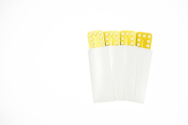 Quatre plaquettes thermoformées de pilules contraceptives dans une enveloppe blanche isolée sur fond blanc avec espace de copie. Concept de planification familiale
. - Photo, image