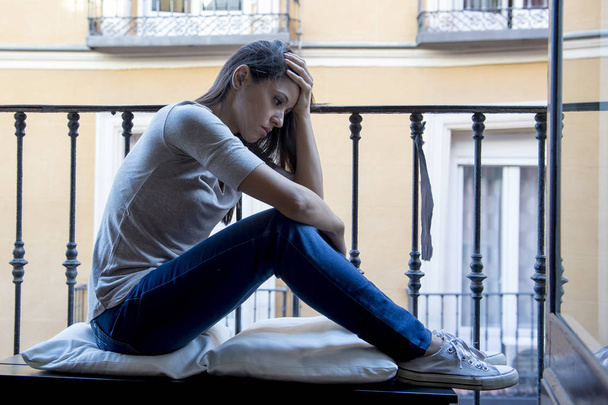 απελπισμένος λυπημένος Λατινική γυναίκα στο σπίτι μπαλκόνι κοιτάζοντας κατέστρεψαν και καταθλιπτικοί υποφέρουν κατάθλιψη - Φωτογραφία, εικόνα