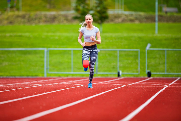 Jovem Feminino em Sportswear correndo em pistas de esportes
 - Foto, Imagem