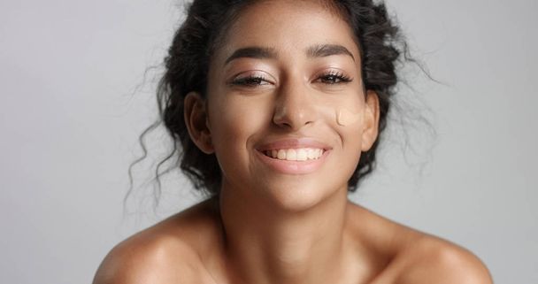 Moyen-Orient jeune femme en studio avec une fondation sur la joue gros plan Toucher la peau
 - Photo, image