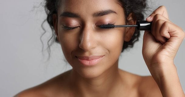 Adorable teenage Middle Eastern girl with great skin applying mascara to her long lashes - Photo, Image