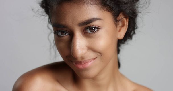 happy serene young woman with beautiful olive skin and curly hair ideal skin and brown eyes in studio - Foto, imagen