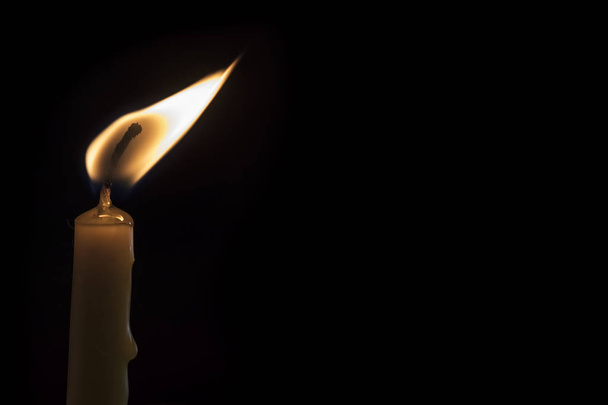 Eine brennende Kerze auf dunklem Hintergrund. - Foto, Bild