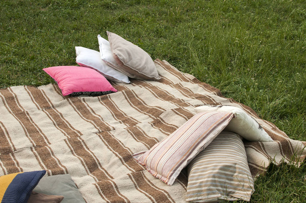 Постельное белье с различными подушками на лугу
 - Фото, изображение
