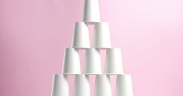 Πύργος κατασκευασμένο από λευκό χαρτί Κύπελλα σε ροζ φόντο - Πλάνα, βίντεο