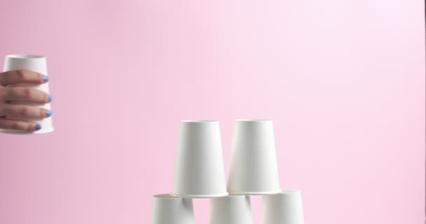 Turm aus weißen Pappbechern auf rosa Hintergrund - Filmmaterial, Video
