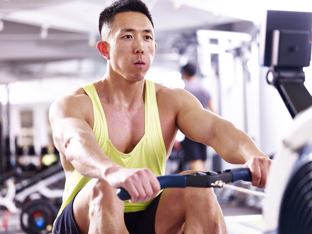young asian man working out using rowing machine - Photo, Image