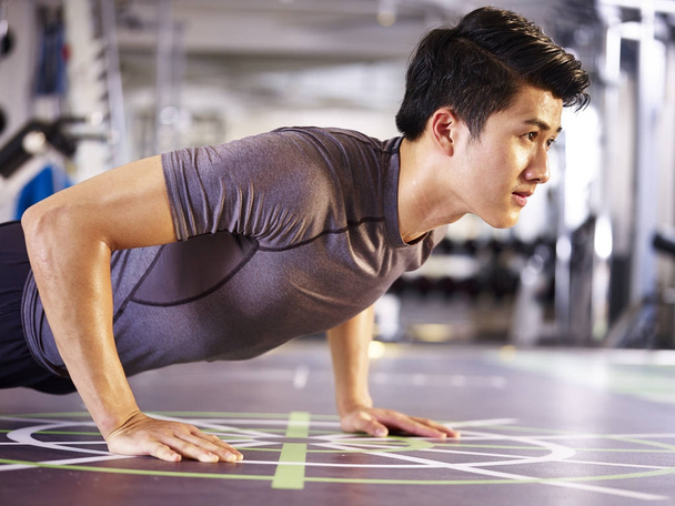 joven asiático hombre haciendo flexiones en gimnasio
 - Foto, imagen