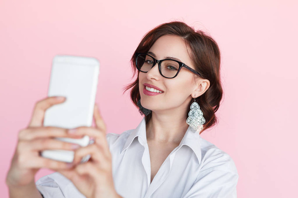 Young woman holding phone making selfie - Фото, изображение