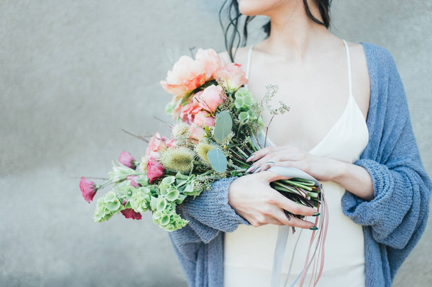 Nainen, jolla on kädessään koristeellinen kukkakimppu
 - Valokuva, kuva