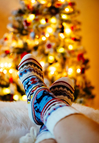 Womans Feet in woollen socks at Christmas tree.  - Foto, Imagen