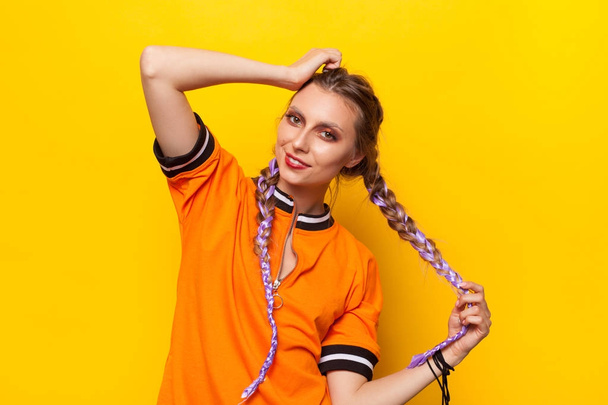 Stylish model with braids posing on orange - Φωτογραφία, εικόνα
