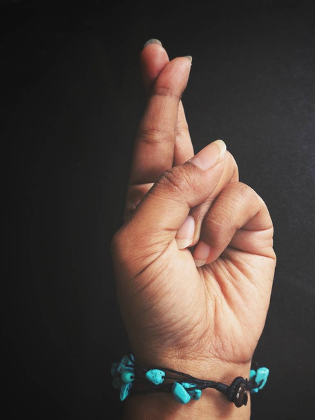 foto recortada de mano femenina con brazalete que muestra el signo de los dedos cruzados en negro
 - Foto, Imagen