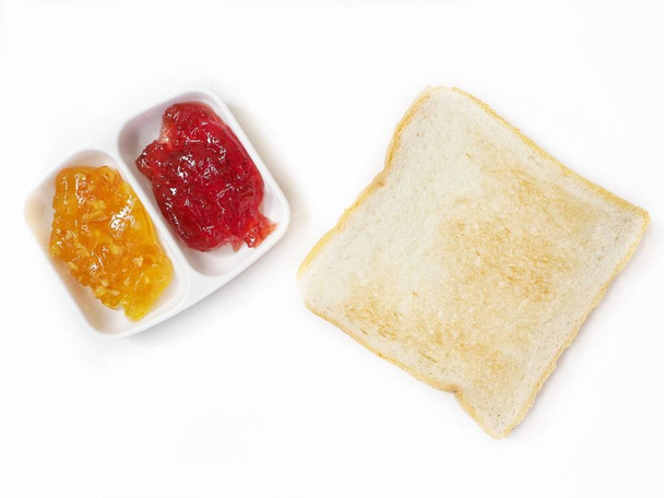 Tranche de pain grillé à la fraise et confiture d'orange isolée sur blanc, vue de dessus
  - Photo, image