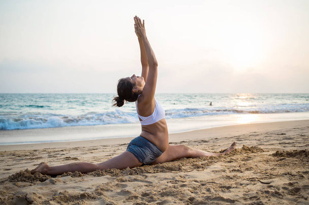 Natural looking pregnant woman practicing yoga at the seashore a - Foto, Imagen