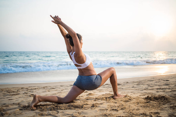 Natural looking pregnant woman practicing yoga at the seashore a - Foto, Bild