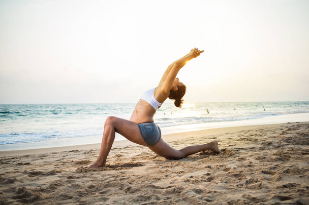 Естественно выглядящая беременная женщина практикующая йогу на берегу моря
 - Фото, изображение