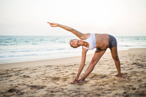 Natural looking pregnant woman practicing yoga at the seashore a - Foto, Imagem