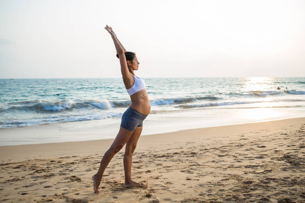 海岸でヨガの練習自然な妊娠中の女性、 - 写真・画像