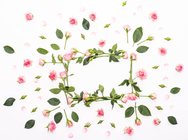Round frame made of pink and beige roses, green leaves, branches, floral pattern on white background. Flat lay, top view. Valentine's background - Foto, immagini