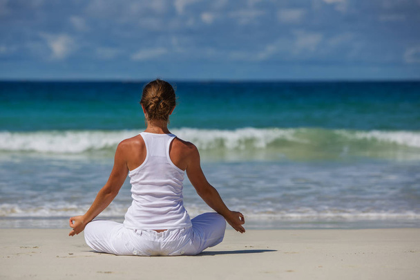 Caucasian woman practicing yoga at seashore of tropic ocean - Foto, immagini