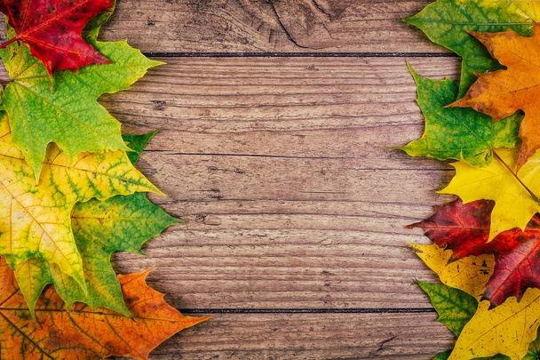 Fond d'automne avec des feuilles d'érable d'automne colorées sur une table en bois rustique. Thanksgiving vacances concept. Feuilles d'automne vertes, jaunes et rouges. Vue du dessus
. - Photo, image