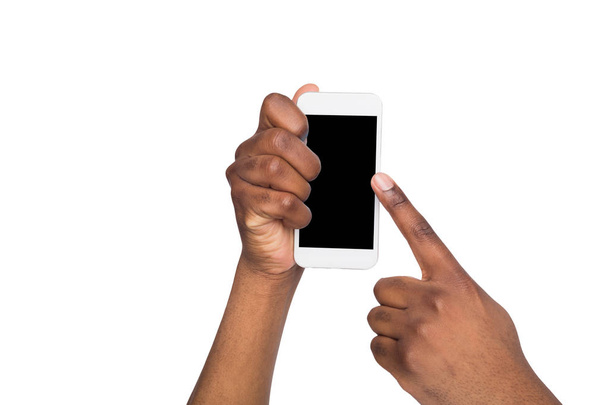 Mano negra sosteniendo el teléfono móvil sobre fondo blanco aislado
. - Foto, imagen