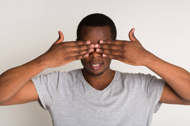Pencive czarny człowiek obejmujących oczy dłońmi - Zdjęcie, obraz