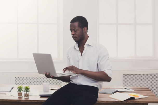 Μαύρο επιχειρηματία σε casual γραφείο, εργασία με φορητό υπολογιστή - Φωτογραφία, εικόνα