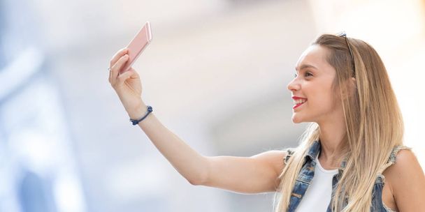 Pretty blonde teenager taking a selfie with her mobile phone. Ho - Photo, Image
