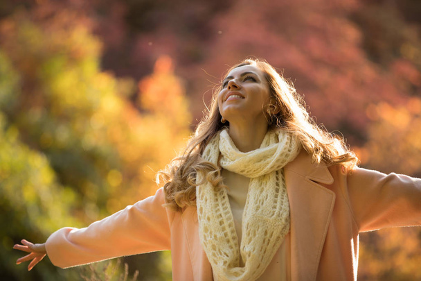 Happy and cheerful woman enjoying autumn, she raise hands - Photo, image