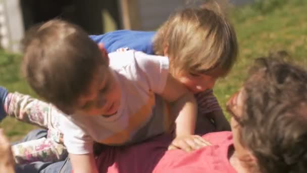 Νεαρό κορίτσι και αγόρι πάλη και τοποθέτηση τον πατέρα τους στο γρασίδι - Πλάνα, βίντεο