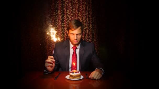 Yalnız bir adam bir tatil kutluyor, o yalnız bir kek ve bir mum ile bir masada oturuyor. 4k, ağır çekim - Video, Çekim