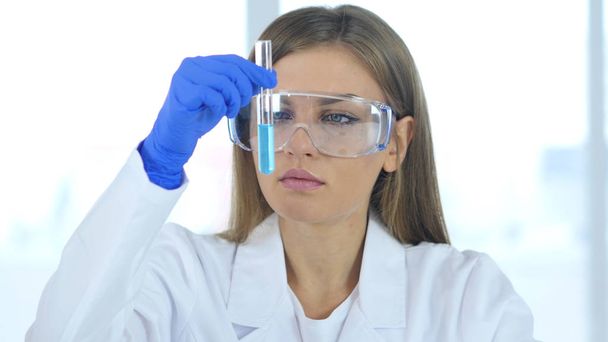 Naispuolinen tutkija, lääkäri etsii Blue Solution in Test Tube laboratoriossa
 - Valokuva, kuva