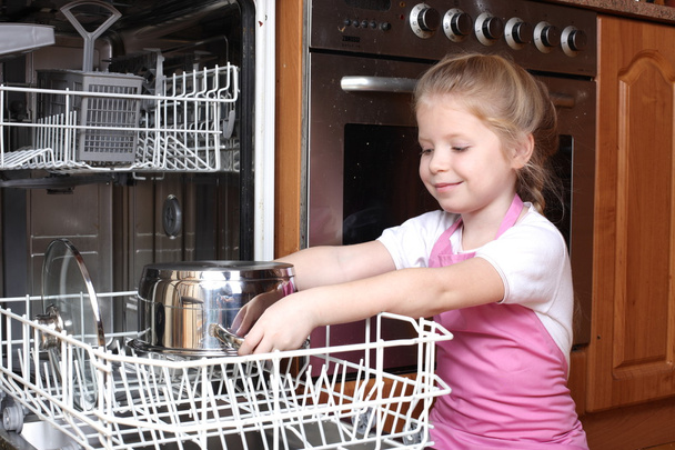 Little girl taken clear glass from dishwasher in the kitchen - Foto, immagini